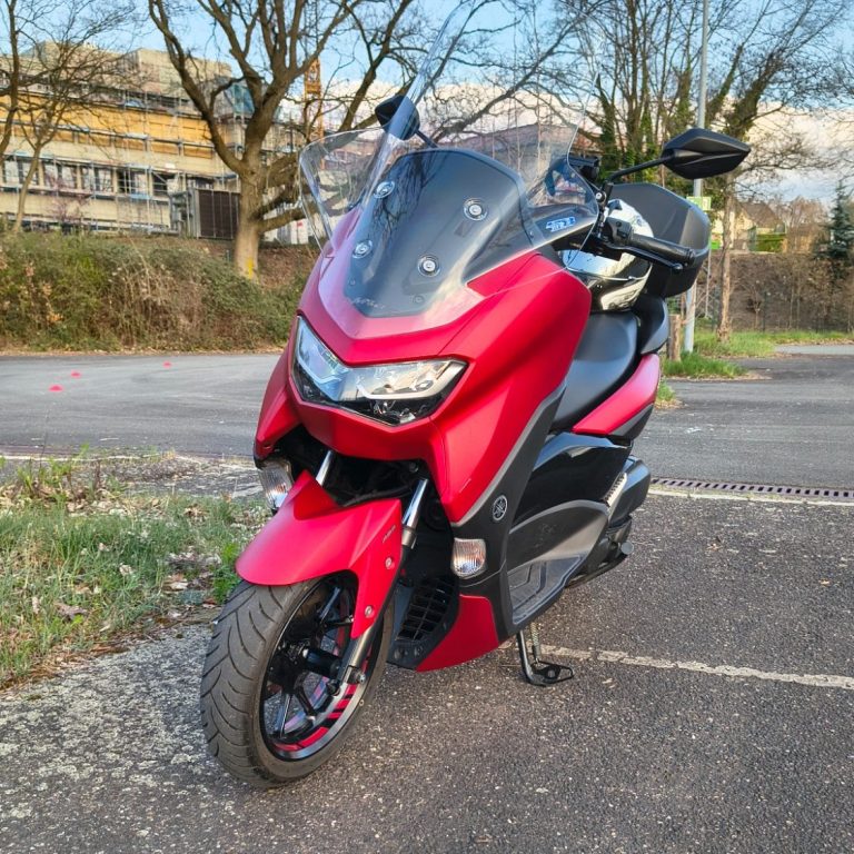Frau sitzt auf einem silbernen Motorrad in einem Verkaufsraum zwischen anderen Motorrädern.
